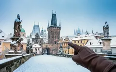 Karlův most v zimě, pohled na Pražský hrad, ruka ukazující na věž v Praze